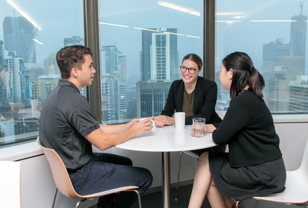 Worley Graduate - Young female professional drinking coffee with her fellow graduates.