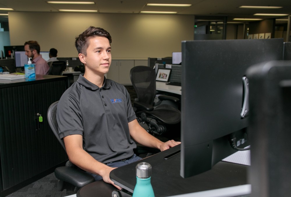 Worley Graduate - Young male professional sitting on his desk.
