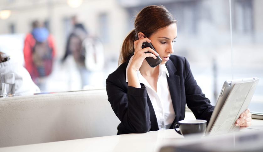Woman sitting at a table holding a mobile phone and folder