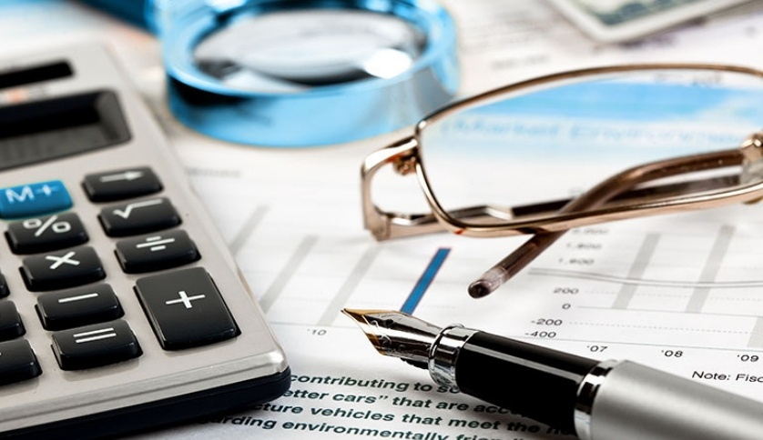 A pen, calculator and eyeglass on top of the table